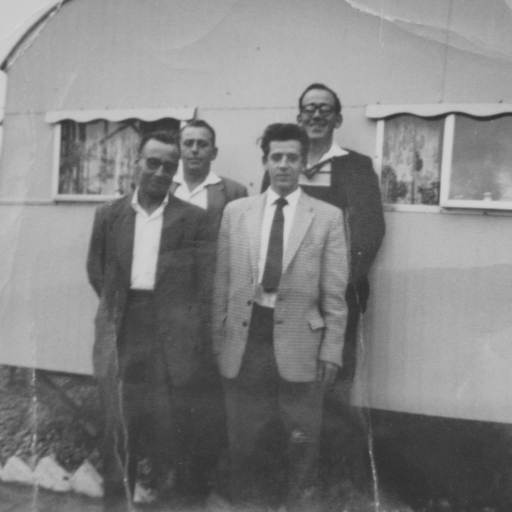 Black and white group shot of my four grand uncles standing in front of an old caravan.